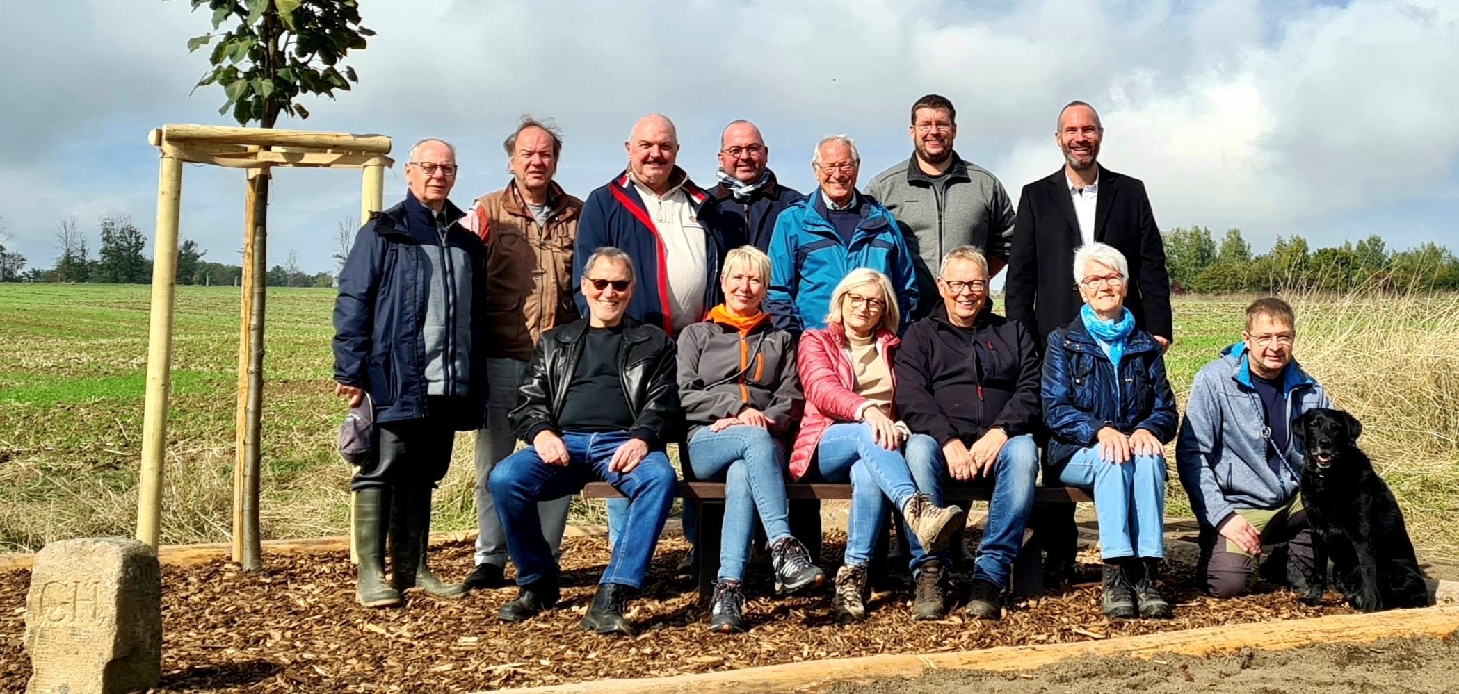 Personen auf einer Holzbank bei einem Feldweg
