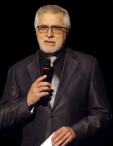 Älterer Mann mit Bart und Brille hält ein Mikrofon in der Hand