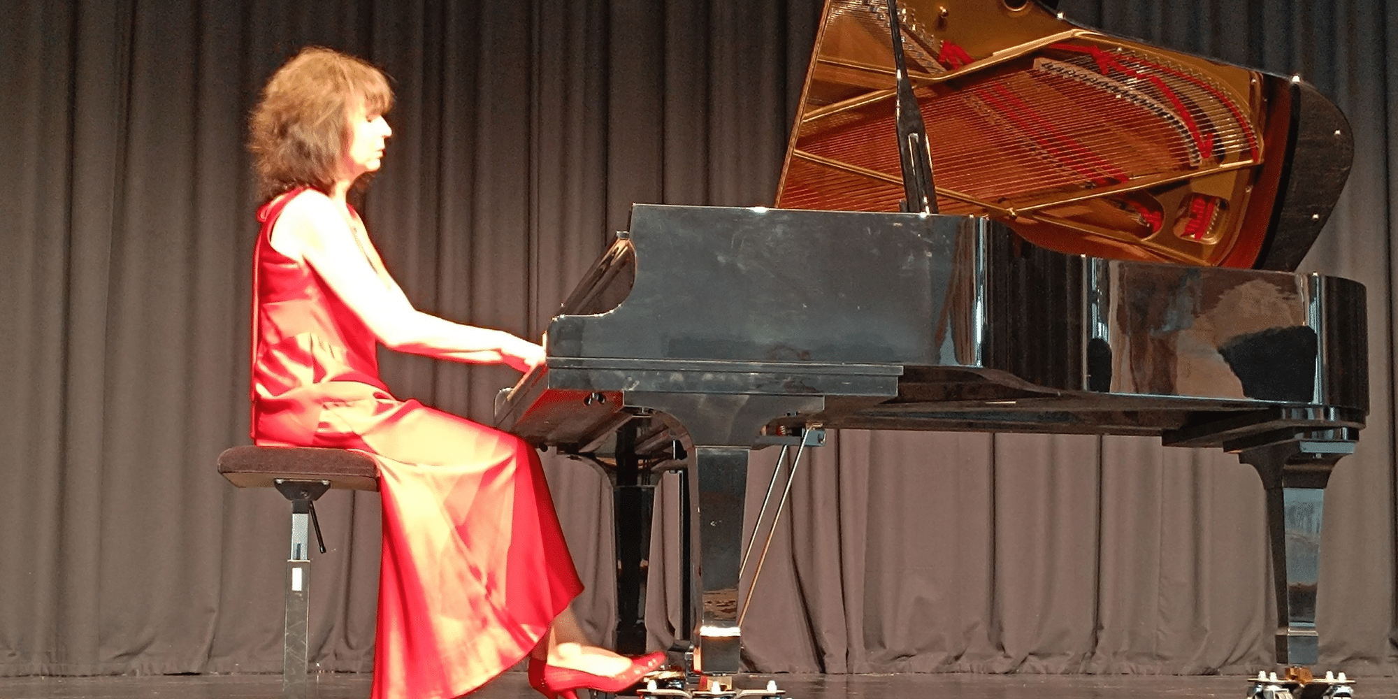 Frau im roten Kleid sitzend am Flügel