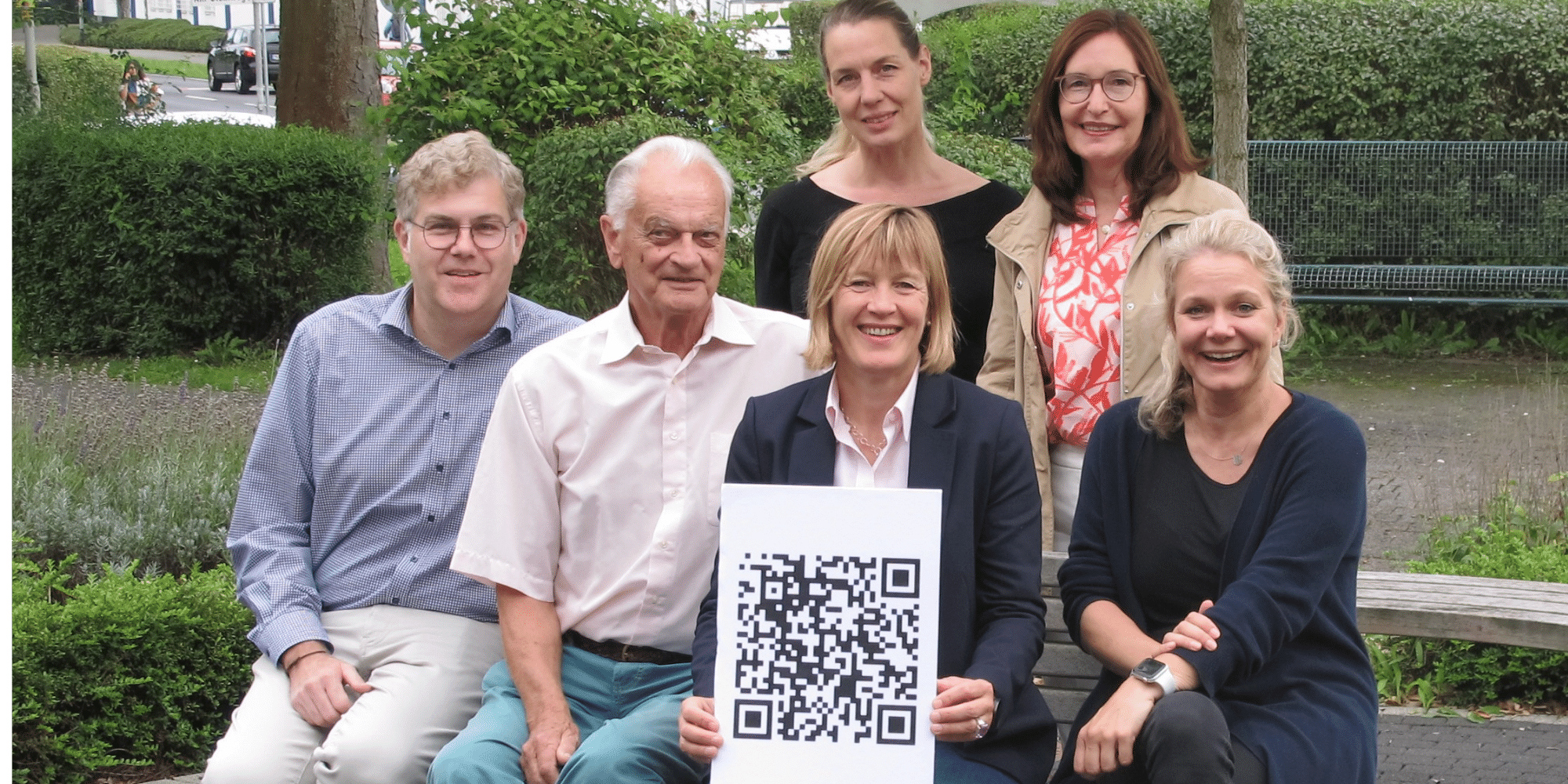 Mehrere Personen sitzend mit einem weiß-schwarzen Poster haltend