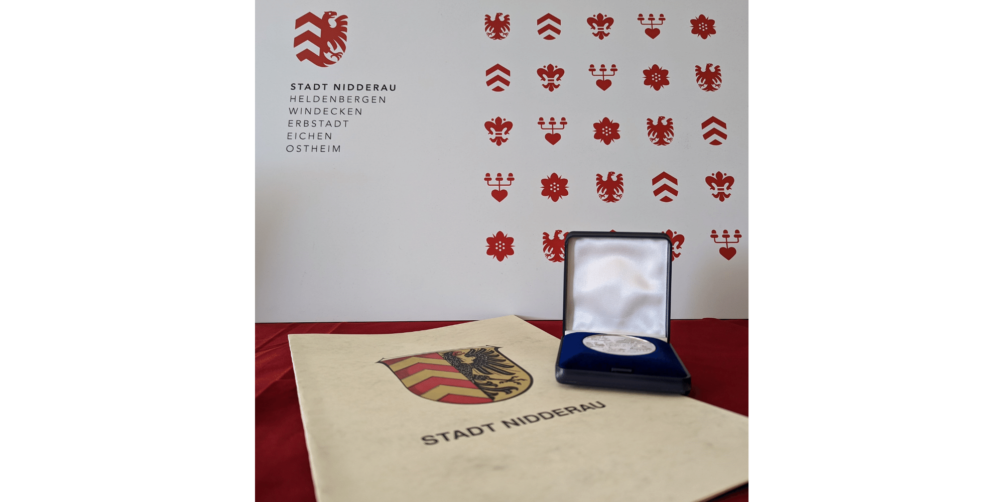 Medaille und Urkunde liegend auf einem Tisch mit rotem Tischtuch