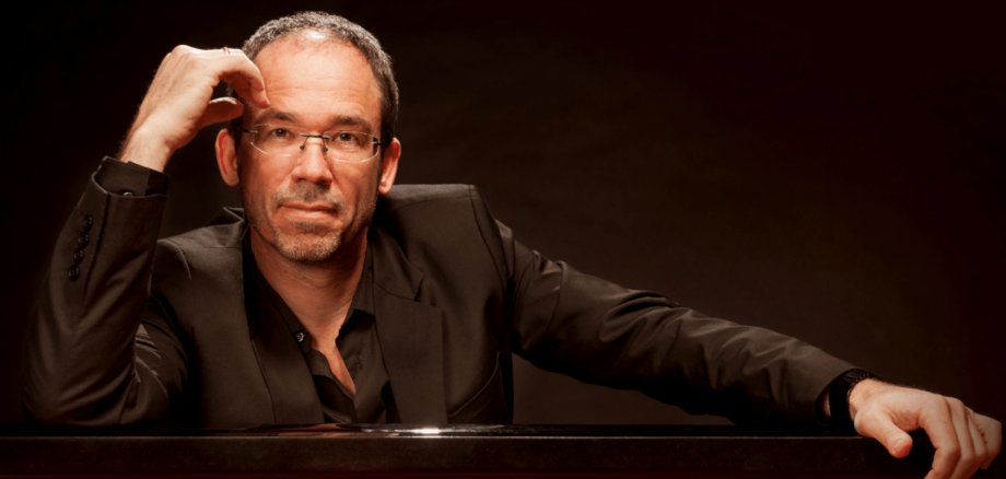 Mann in schwarzem Anzug und Brille sitzend