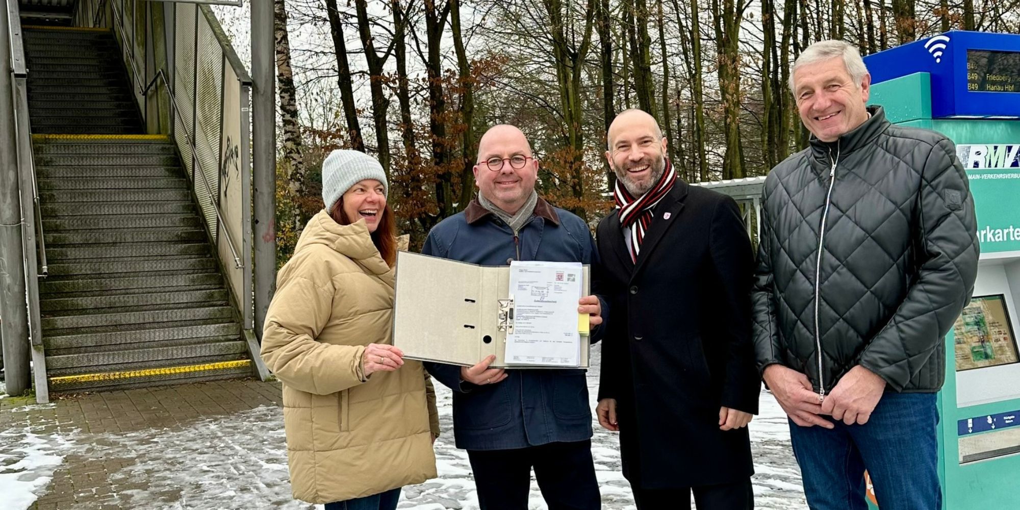4 Menschen stehen vor einem Fahrkartenautomaten und halten Förderbescheid in die Kamera