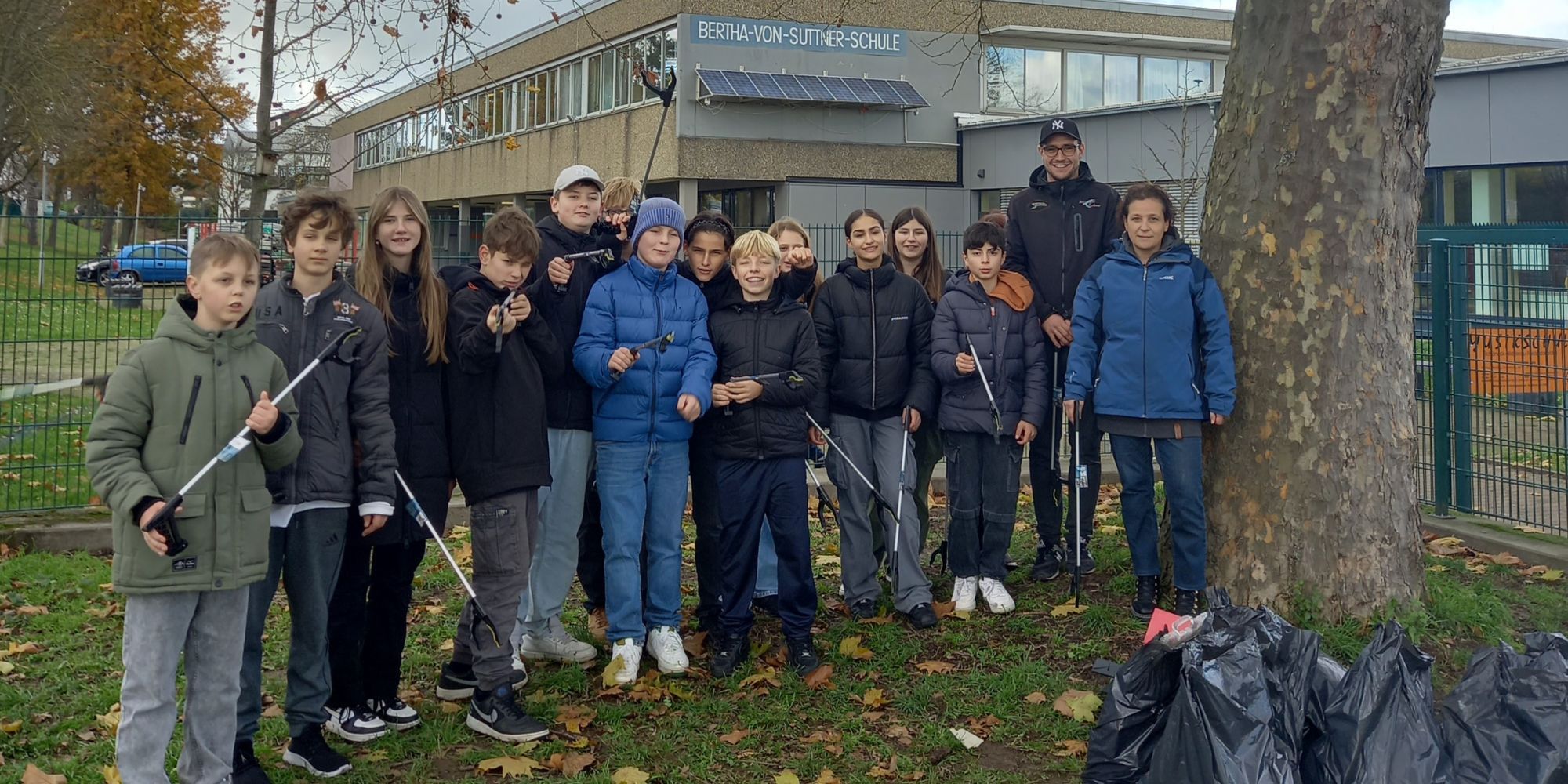 Gruppenfoto: Schüler mit Müllsäcken und Greifzangen vor dem Schulgebäude