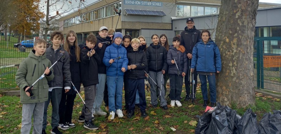 Gruppenfoto: Schüler mit Müllsäcken und Greifzangen vor dem Schulgebäude