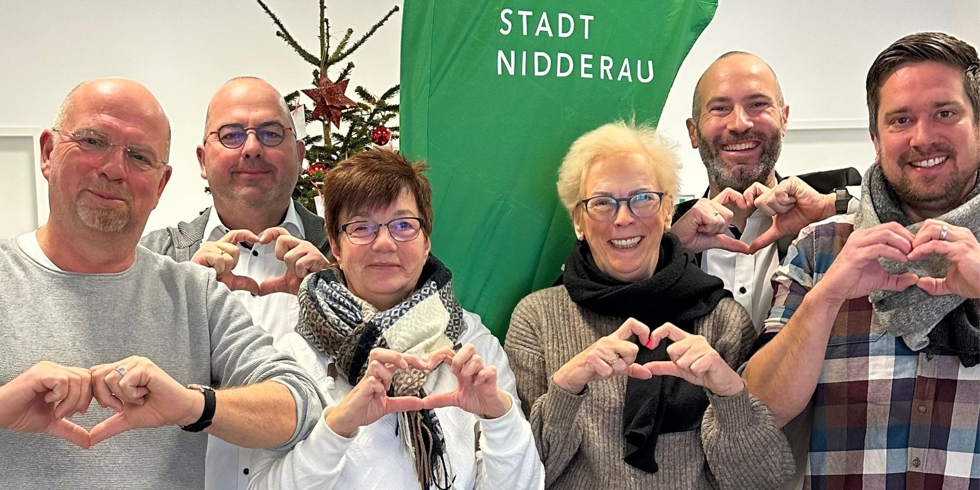 6 Personen vor grüner Nidderau-Beachflag formen Herz mit der Hand