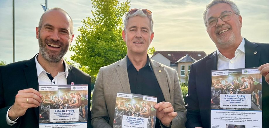 3 Männer halten Veranstaltungsplakate hoch