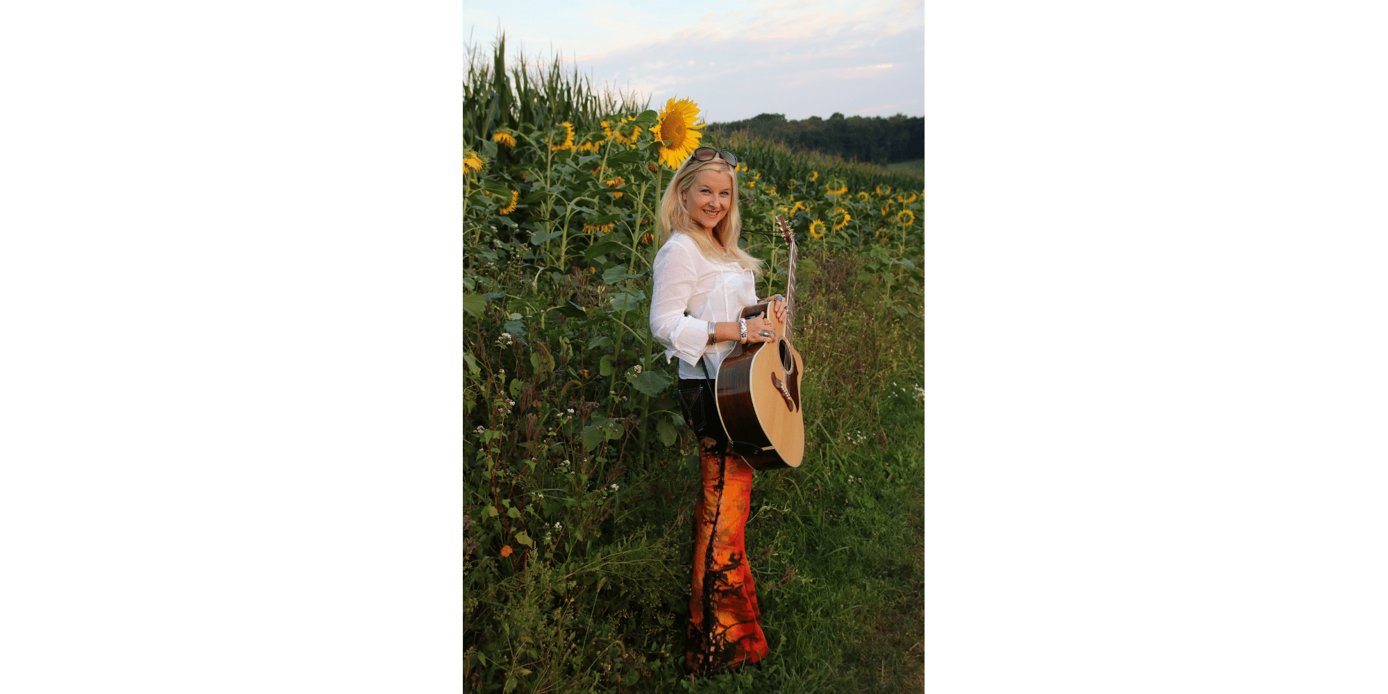 Blonde Frau mit Gitarre, stehend im Sonnenblumenfeld