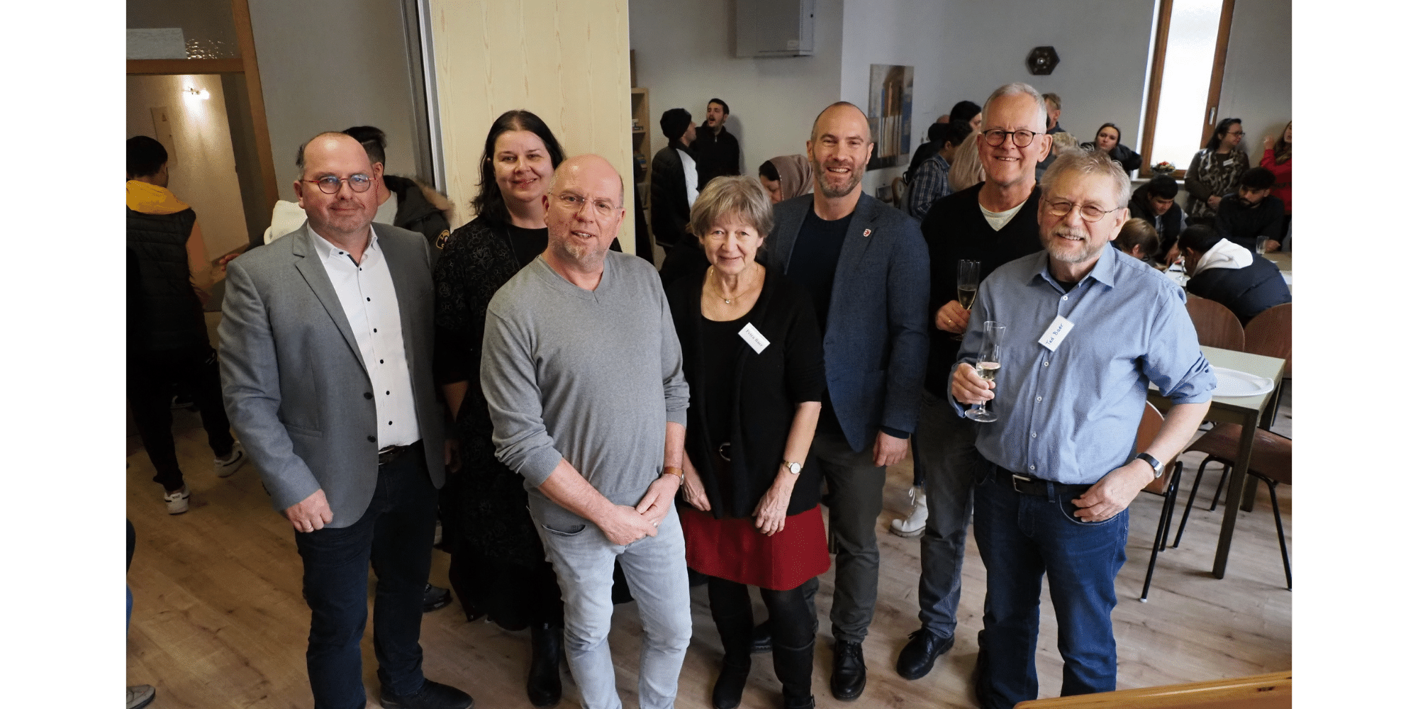 Städtische Mitarbeiter  stehen lächelnd nebeneinander im Café