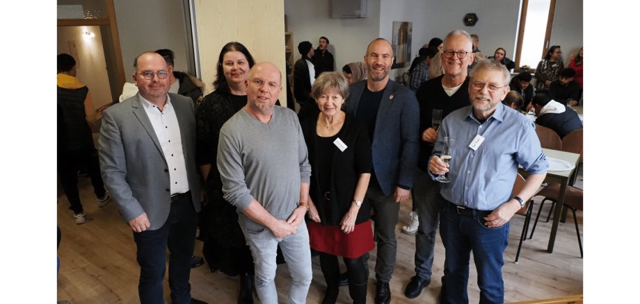 Städtische Mitarbeiter  stehen lächelnd nebeneinander im Café