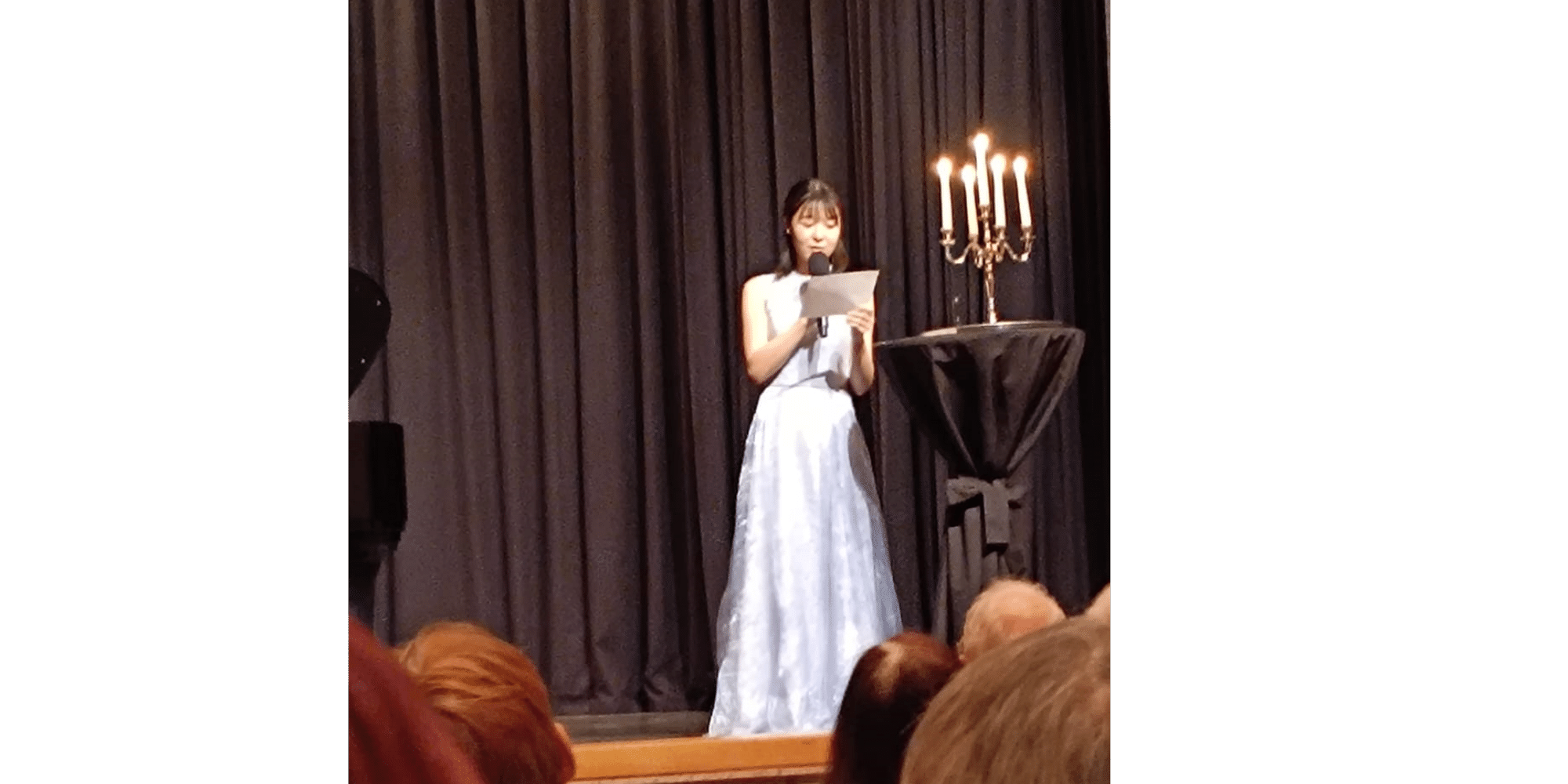 Frau steht mit einem Mikrofon auf einer Bühne