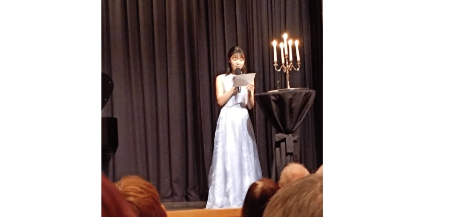 Frau steht mit einem Mikrofon auf einer Bühne