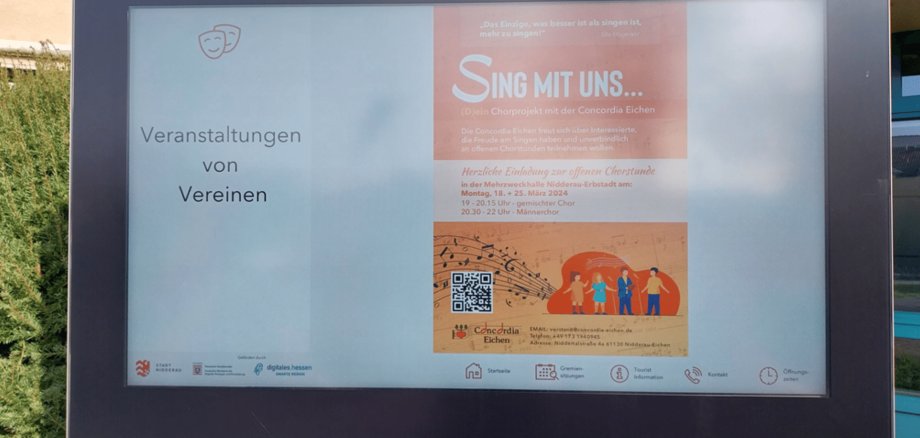 Digitales Display vor dem Rathaus mit einem orangenen Plakat einer Vereins-Veranstaltung