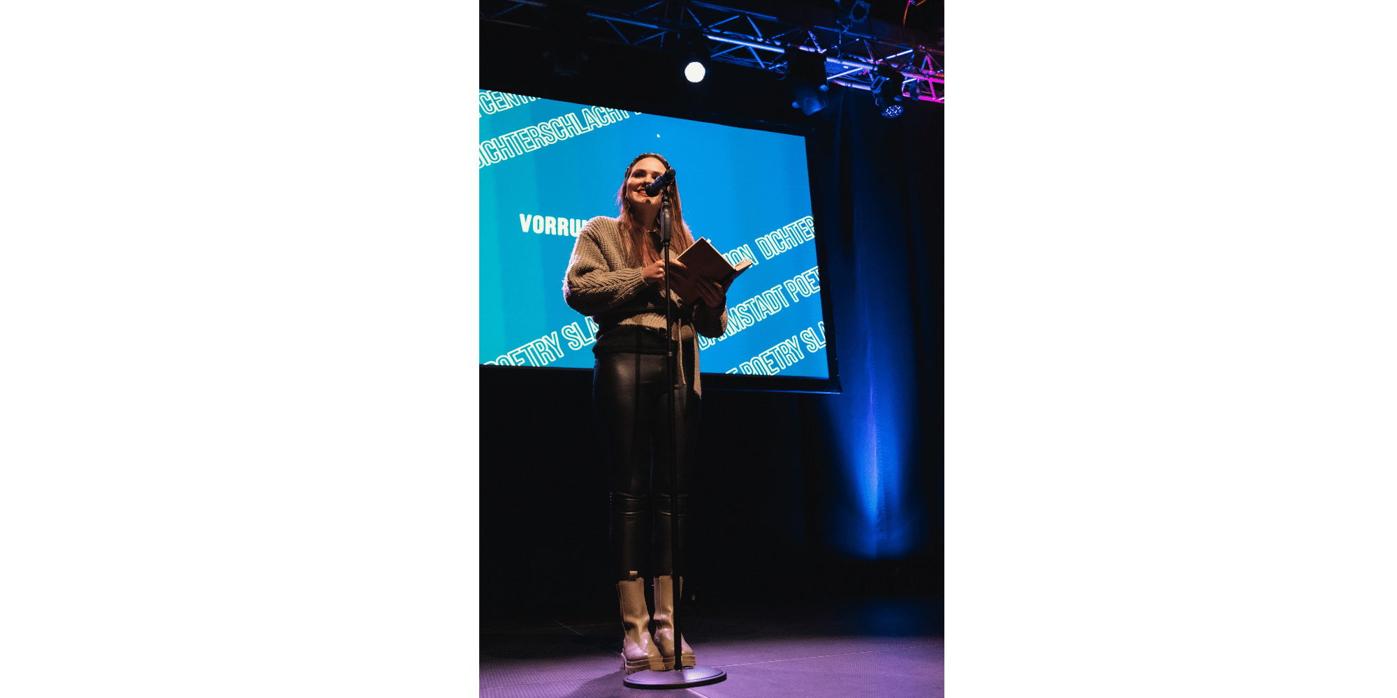 Frau stehend auf einer Bühne vor einem Mikrofon