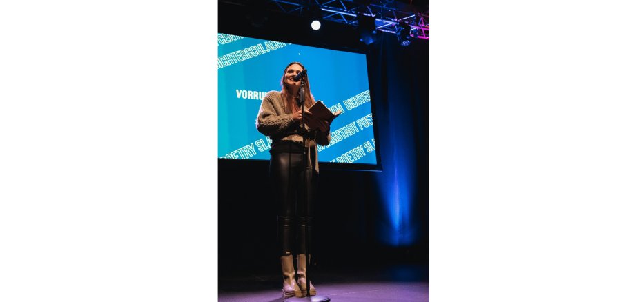 Frau stehend auf einer Bühne vor einem Mikrofon