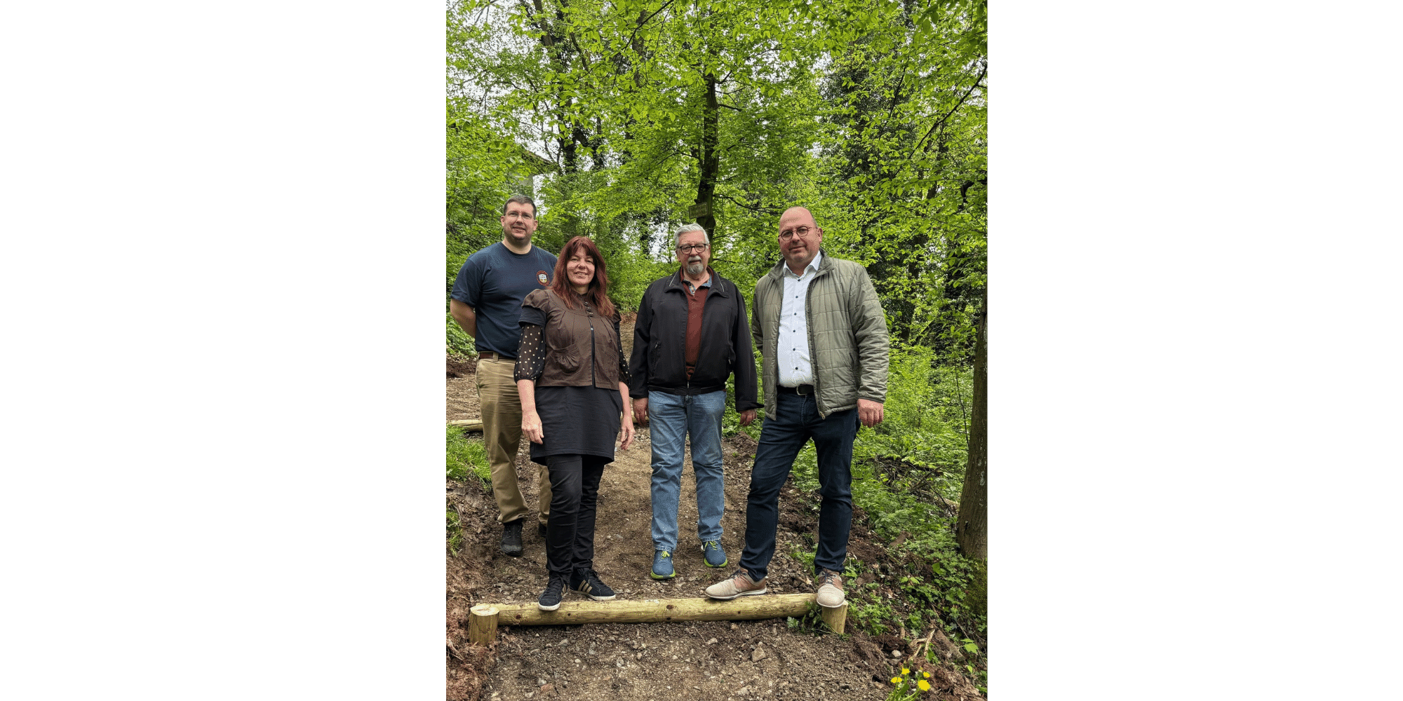 3 Männer und 1 Frau stehend auf einem Waldpfad