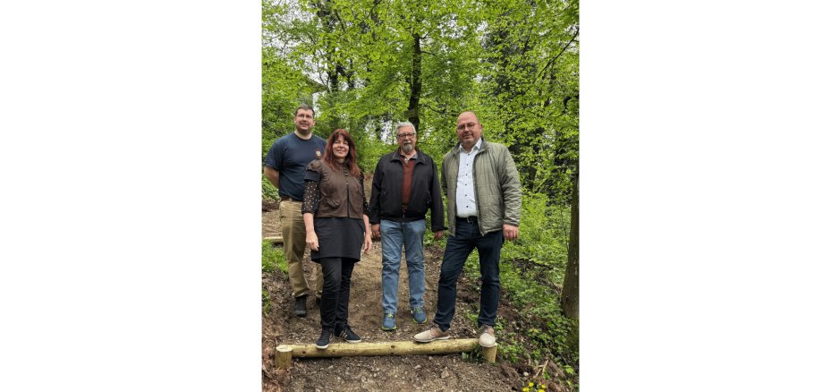 3 Männer und 1 Frau stehend auf einem Waldpfad