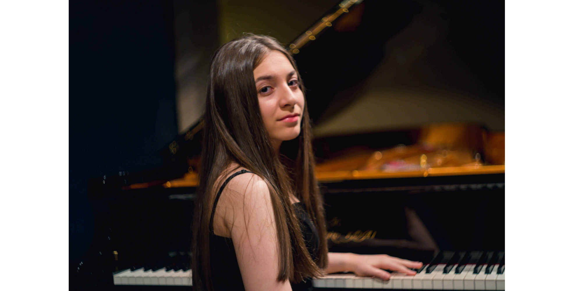 Junge Frau mit langen Haaren sitz am Klavier