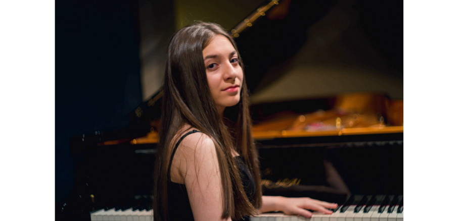 Junge Frau mit langen Haaren sitz am Klavier