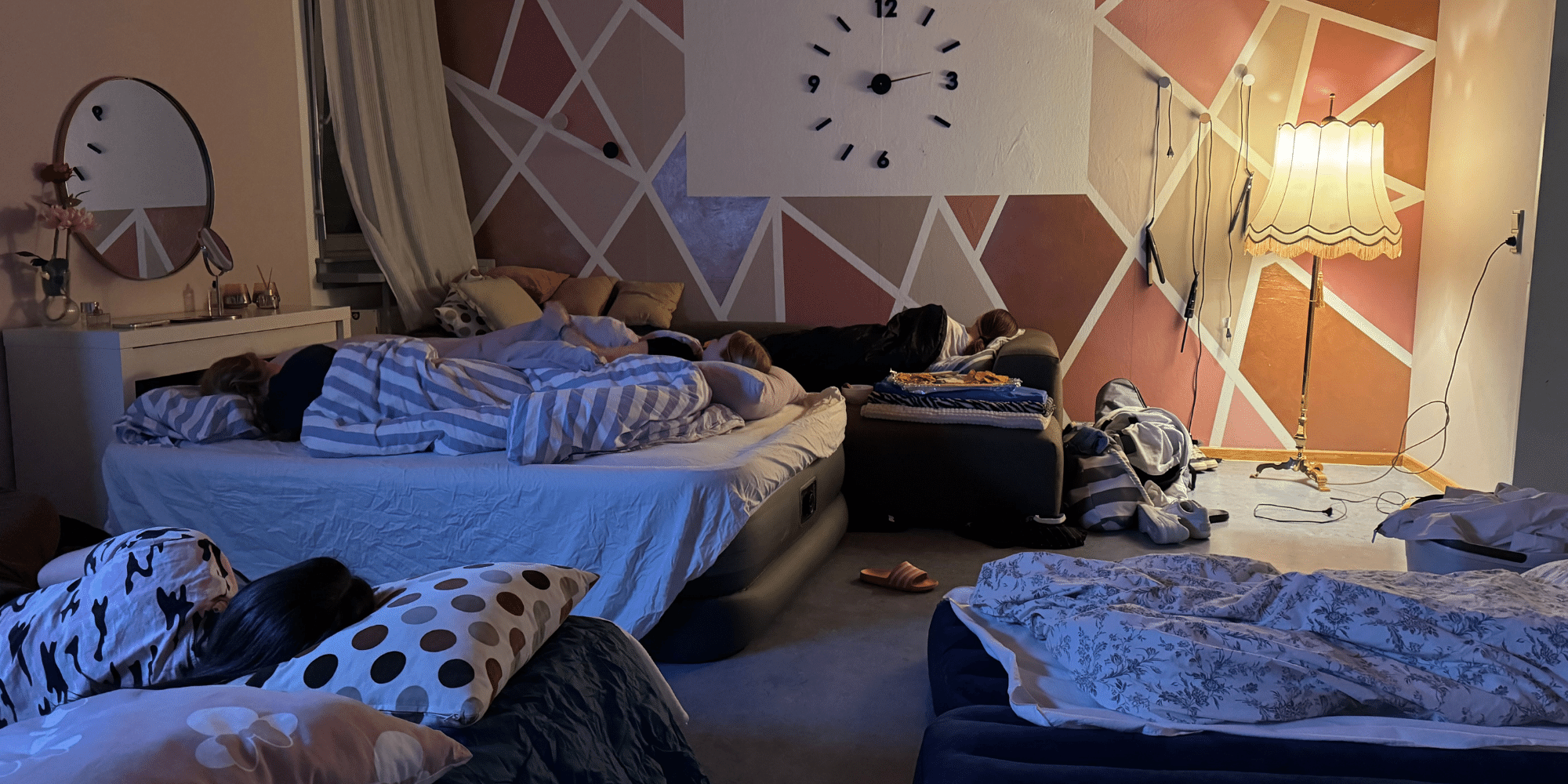 Mehrere Personen auf einzelnen Luftmatratzen  liegend in einem beleuchteten Raum