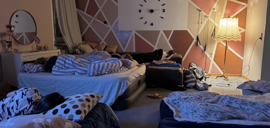 Mehrere Personen auf einzelnen Luftmatratzen  liegend in einem beleuchteten Raum