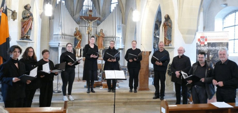 Mehrere Personen schwarz gekleidet mit Mappen in den Händen in einer Kirche