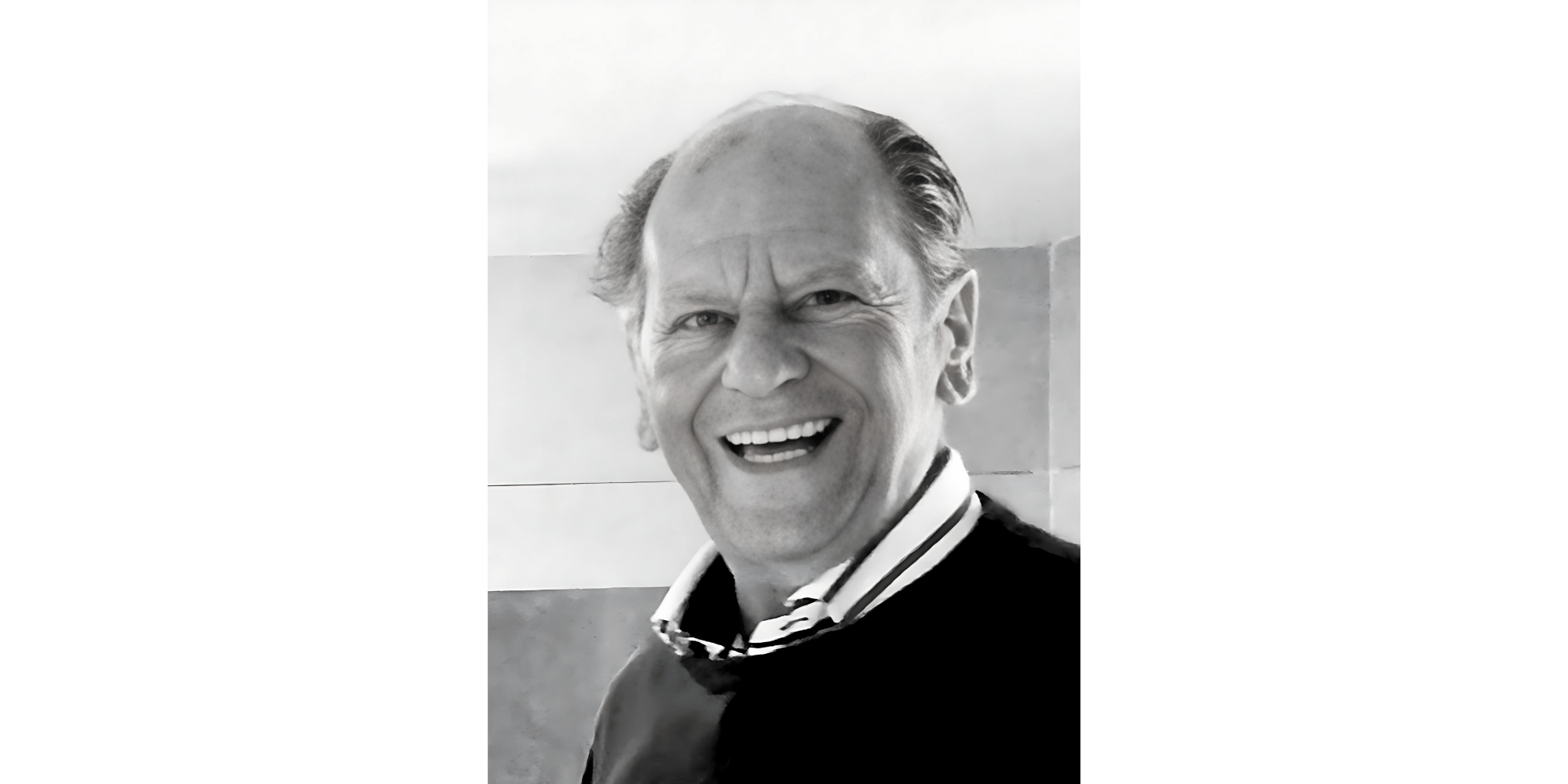 Porträt eines Mannes lächelnd mit dunklem Pullover, das Foto ist eine schwarz-weiß-Aufnahme