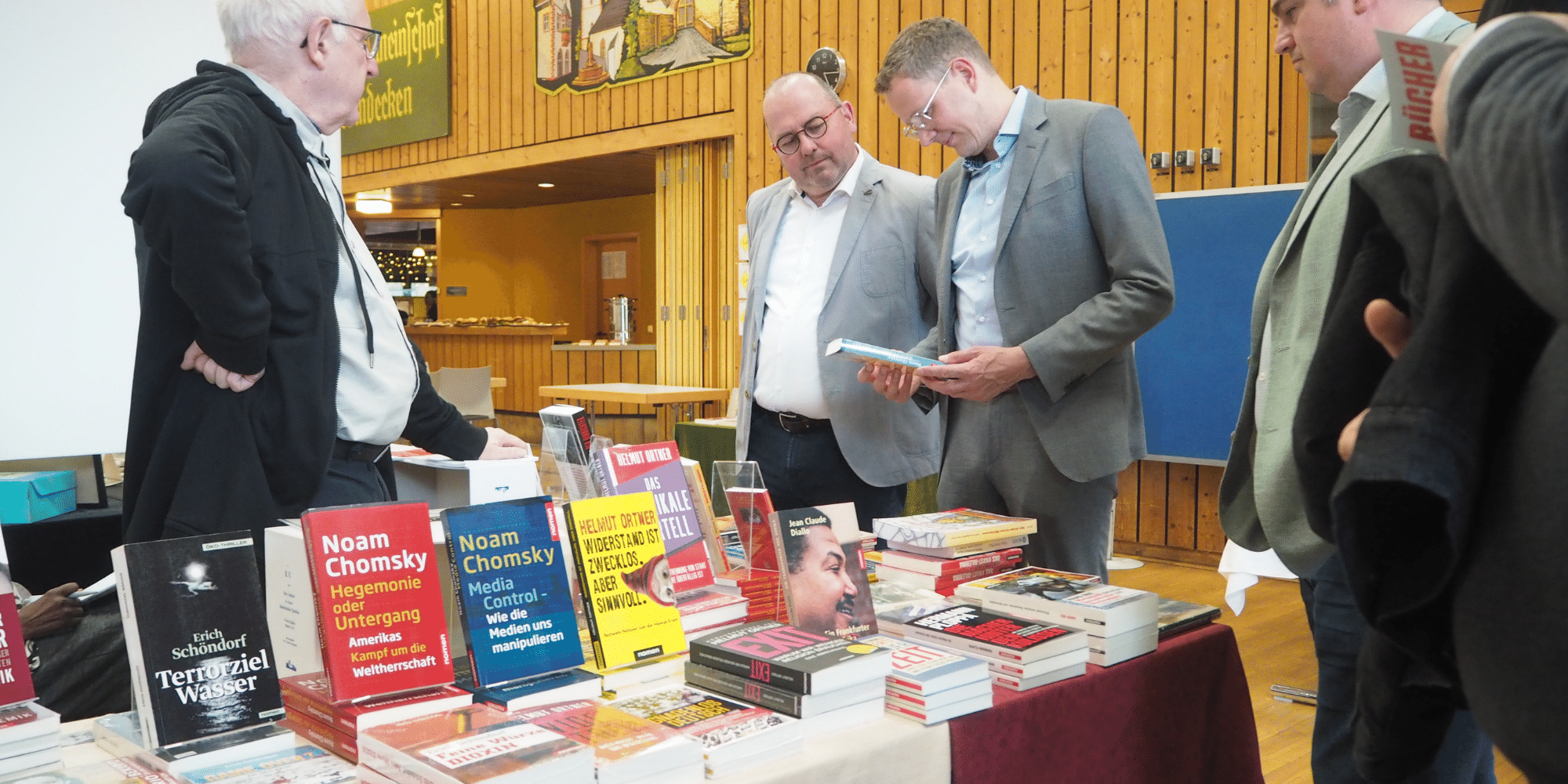 Mehrere Männer stehend vor einem Tisch mit vielen Büchern