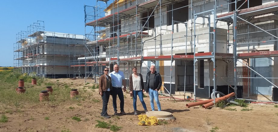 Zwei Frauen und zwei Männer stehend vor einem Rohbau auf einer Baustelle