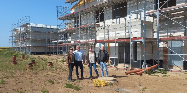 Zwei Frauen und zwei Männer stehend vor einem Rohbau auf einer Baustelle