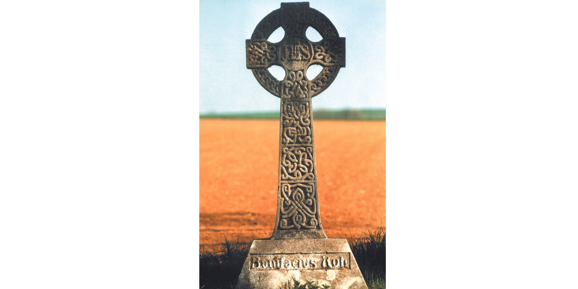 Altes Kreuz aus Stein vor einem Feld