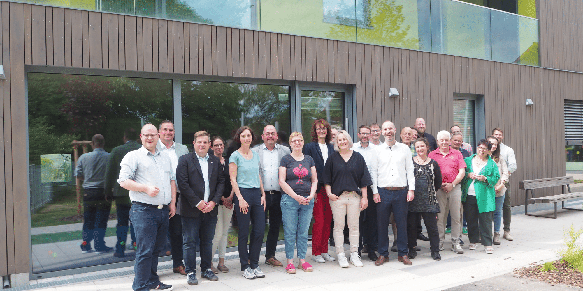 Mehrere Leute stehend vor der Außenfassade des neuen Kitagebäudes in Eichen