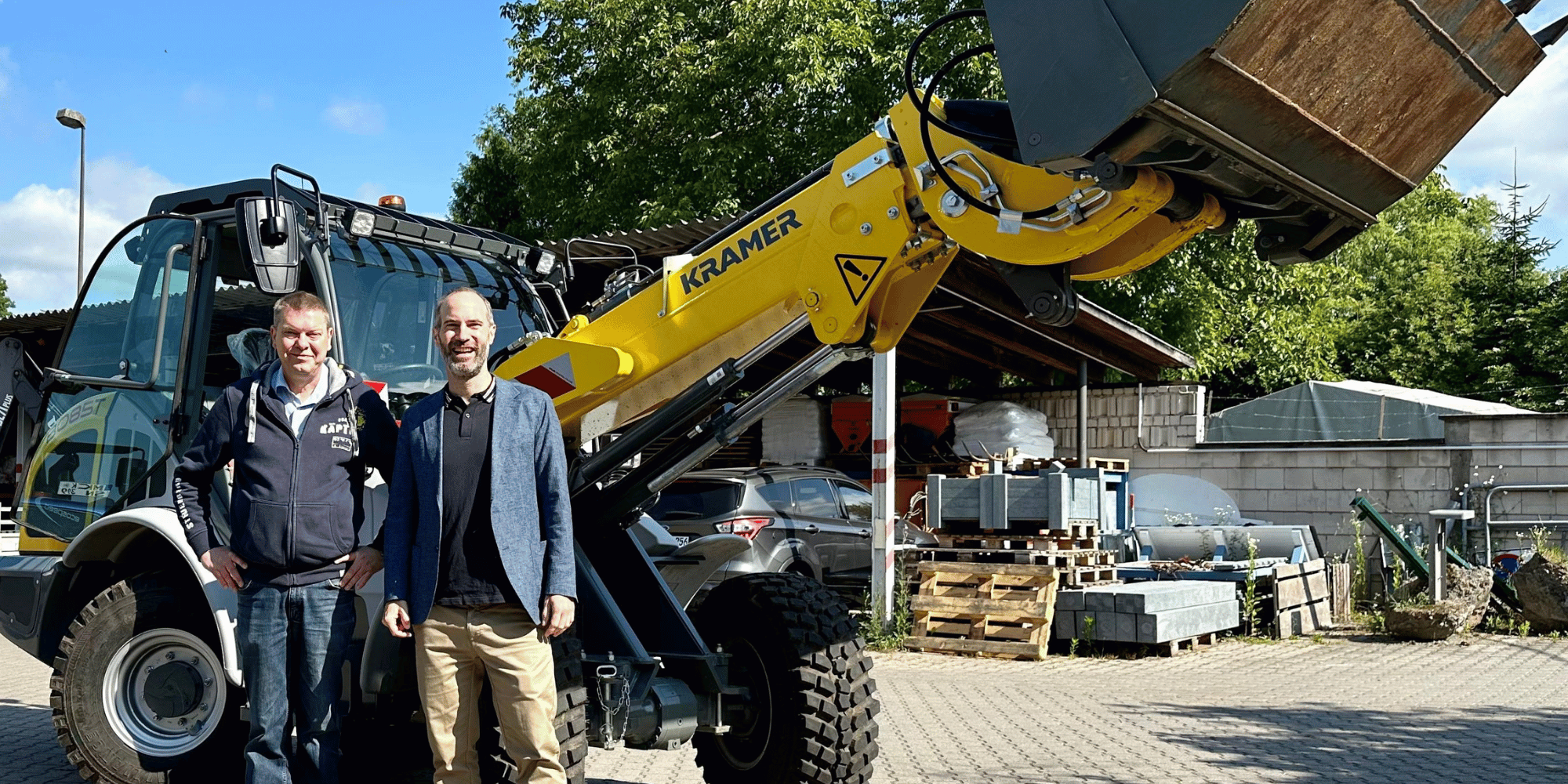 Radlader und davor zwei Männer stehend