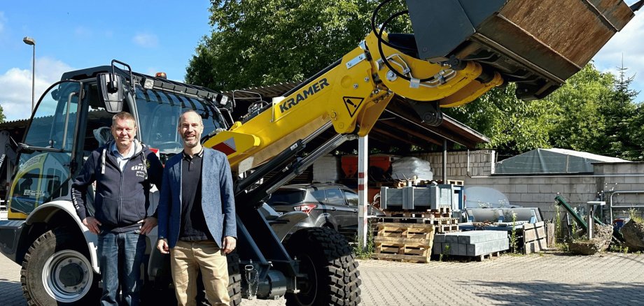 Radlader und davor zwei Männer stehend