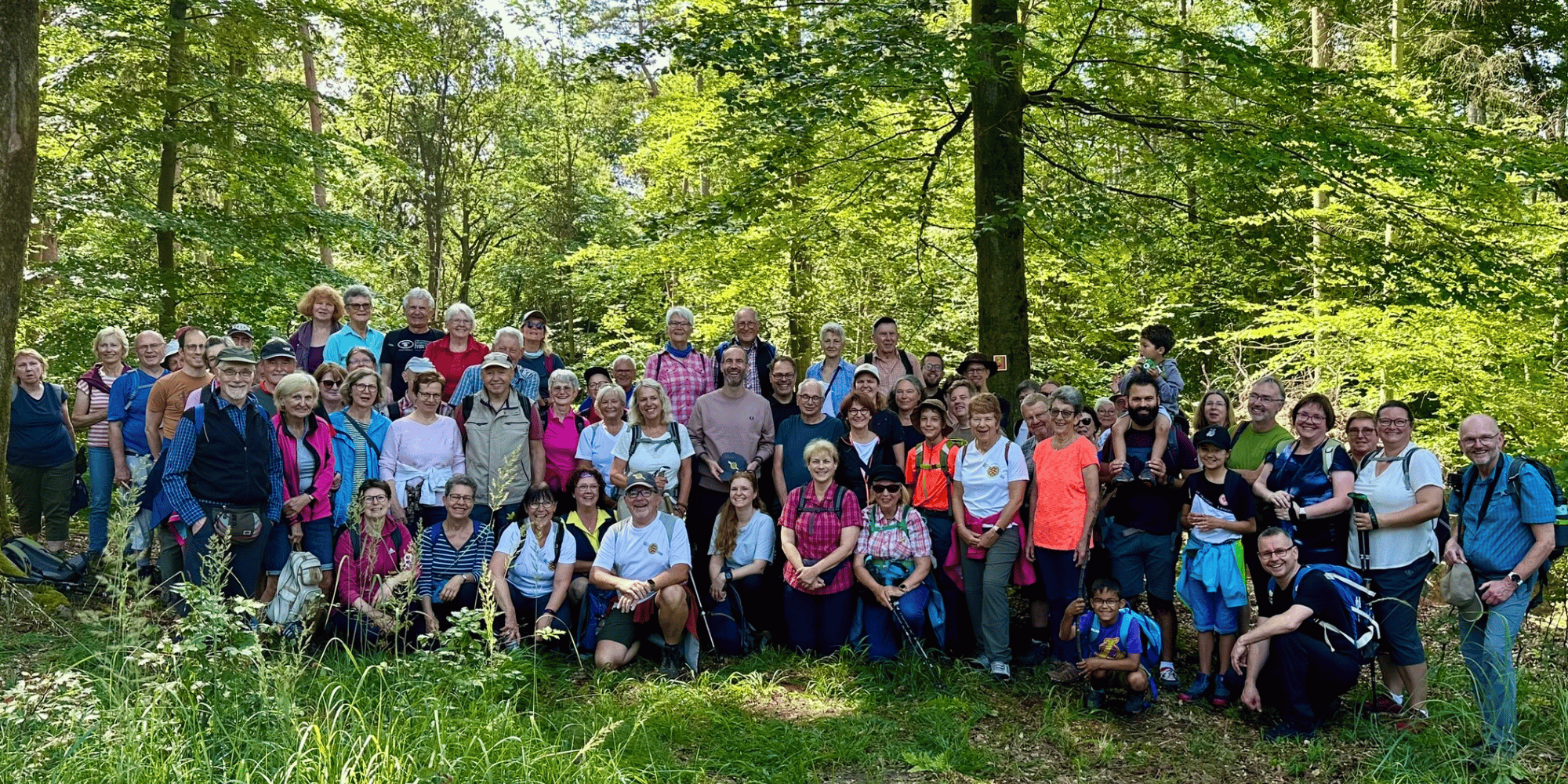 Viele Personen zusammenstehend vor einem Wald
