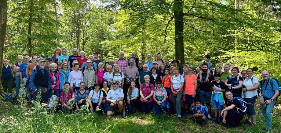 Viele Personen zusammenstehend vor einem Wald