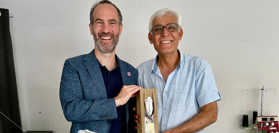 Mann überreicht eine Weinflasche als Präsent an einen anderen Mann