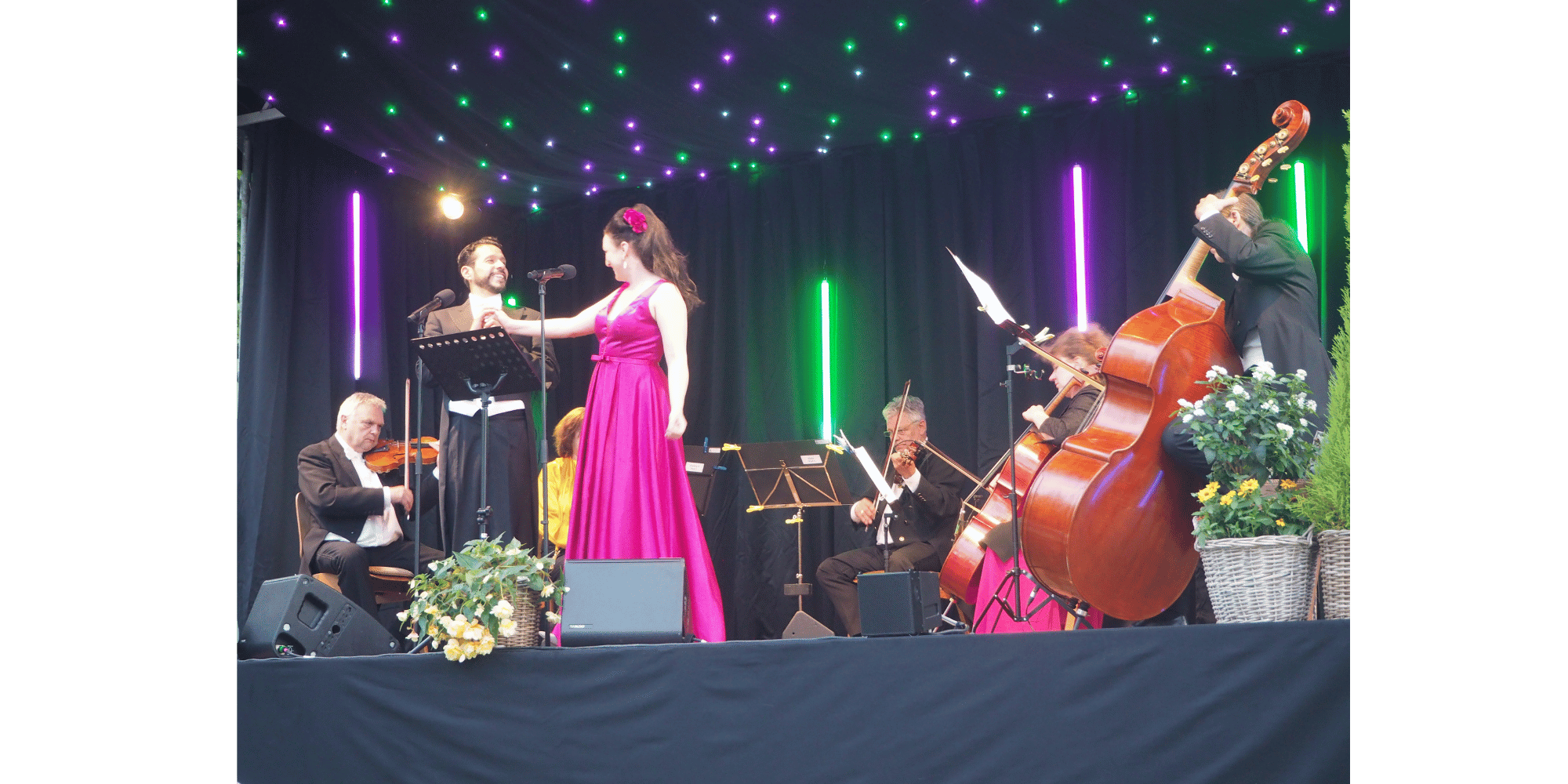 Männer und Frauen mit Instrumenten auf einer Bühne