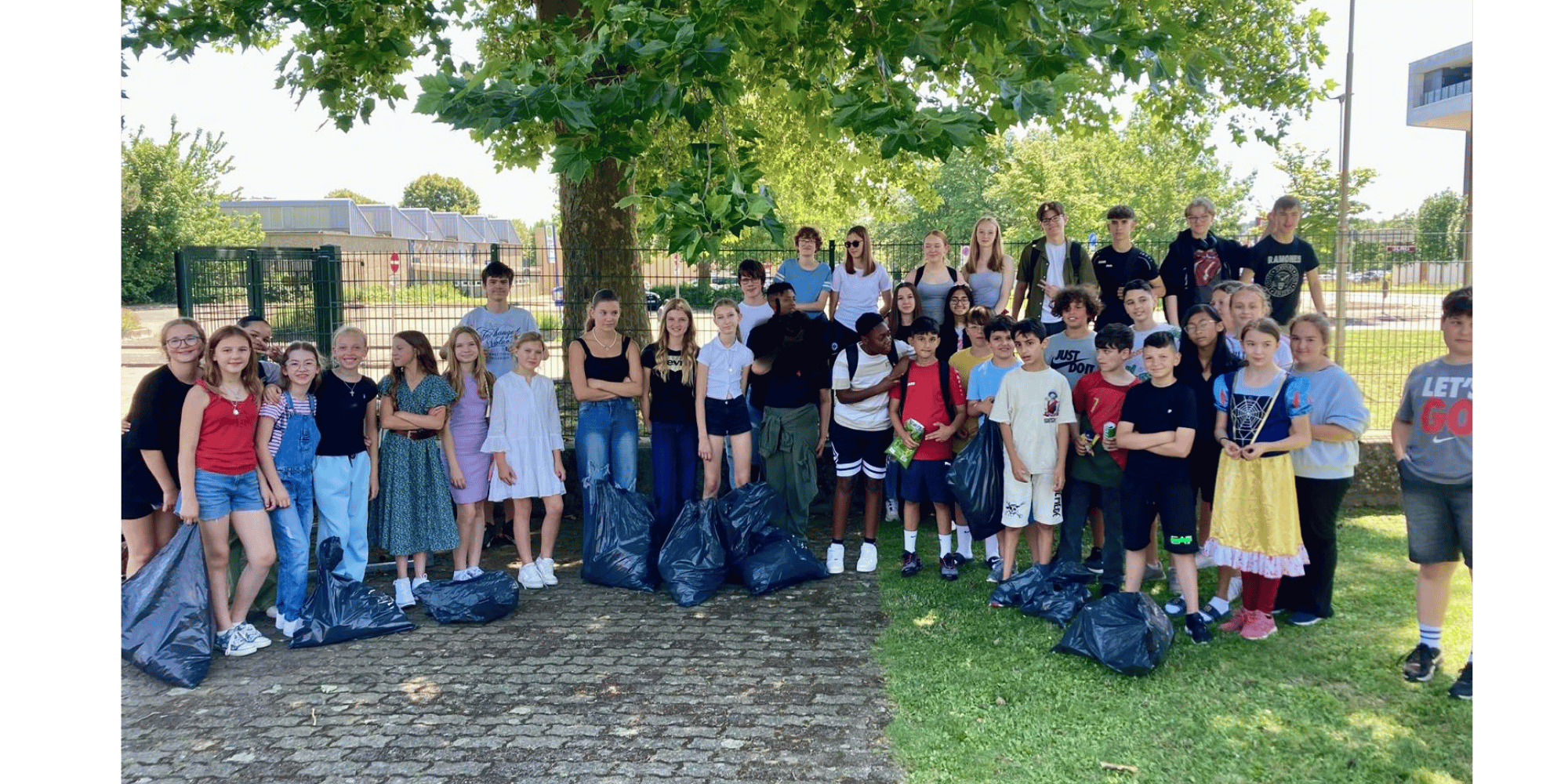 viele Kinder mit Müllsäcken stehend auf einem Schulhof