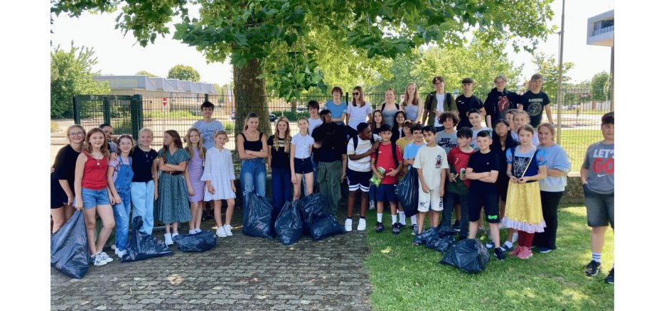 viele Kinder mit Müllsäcken stehend auf einem Schulhof