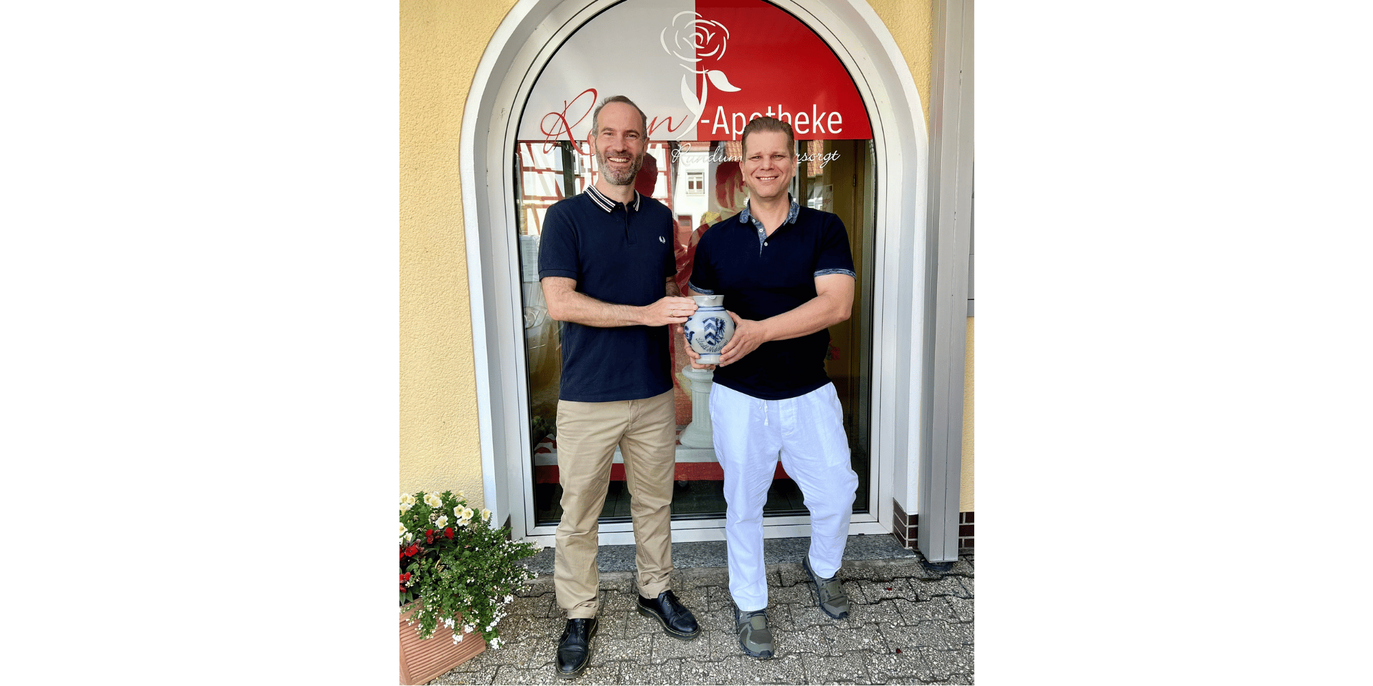 2 Männer stehend vor einem Haus mit einem Krug in den Händen