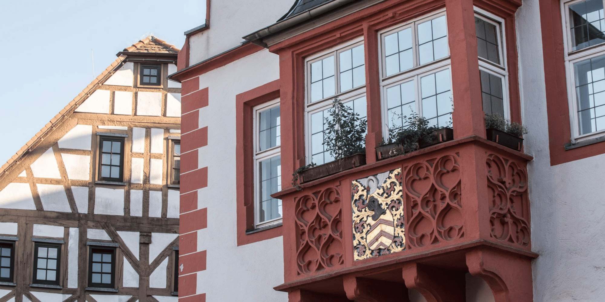 Außenfassade eines alten Hauses mit Balkon und Wappen