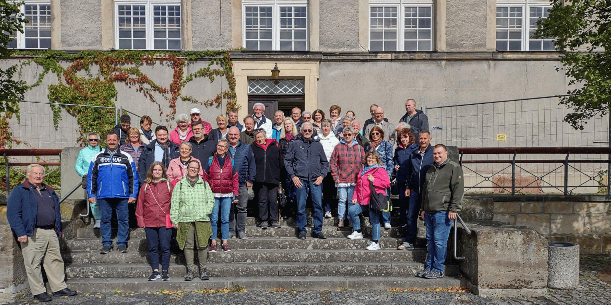 Mehrere Personen stehend auf einer Steintreppe vor einem Haus