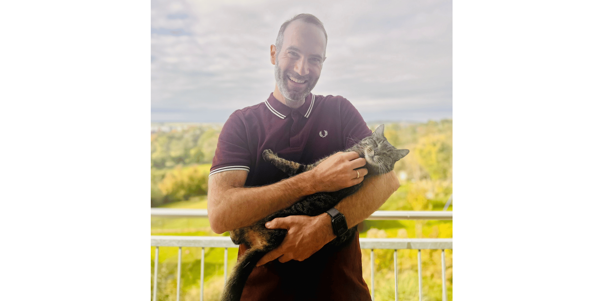 Mann stehend mit Katze im Arm 