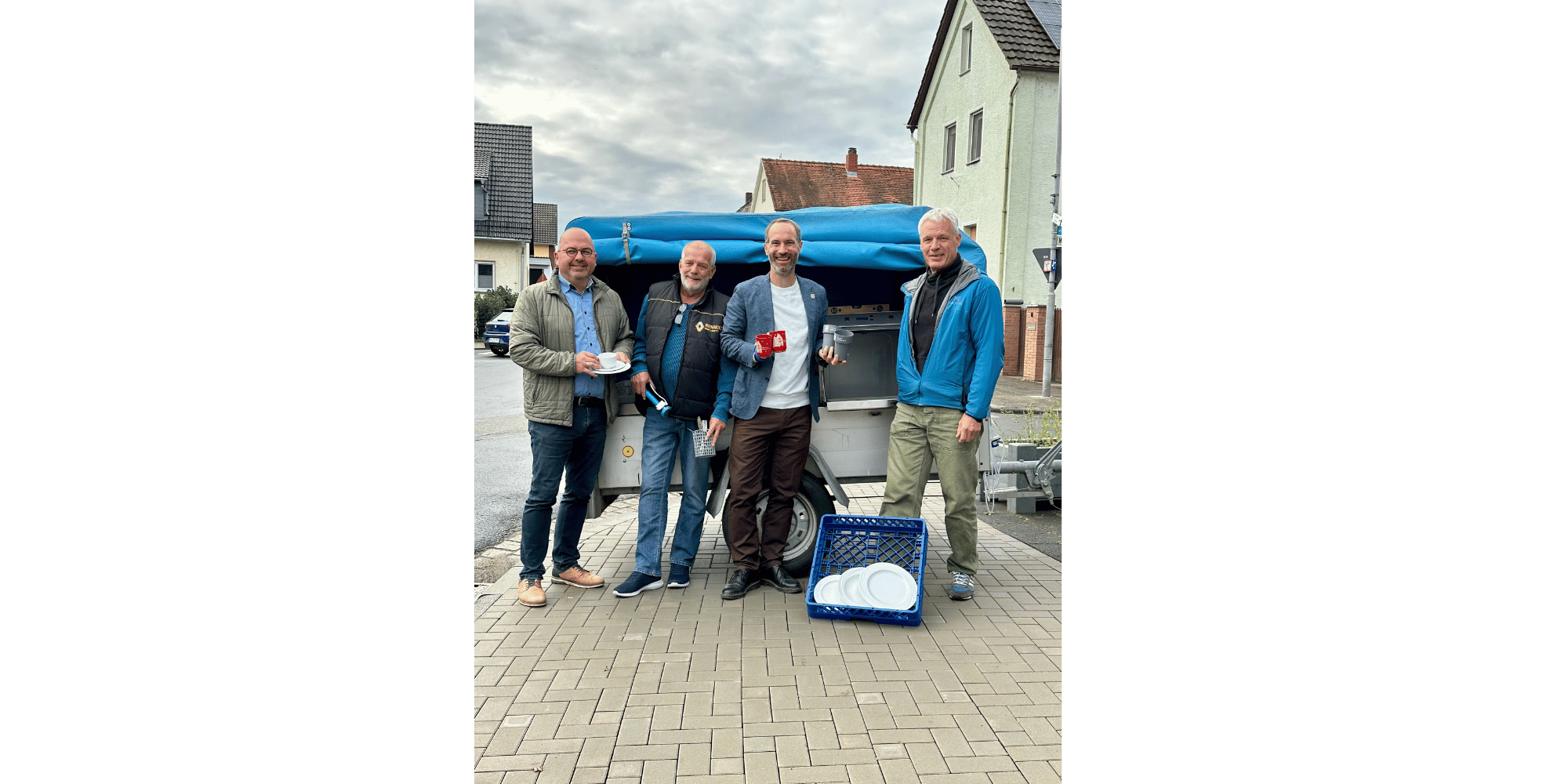 4 Männer stehend mit Geschirr vor einem Anhänger