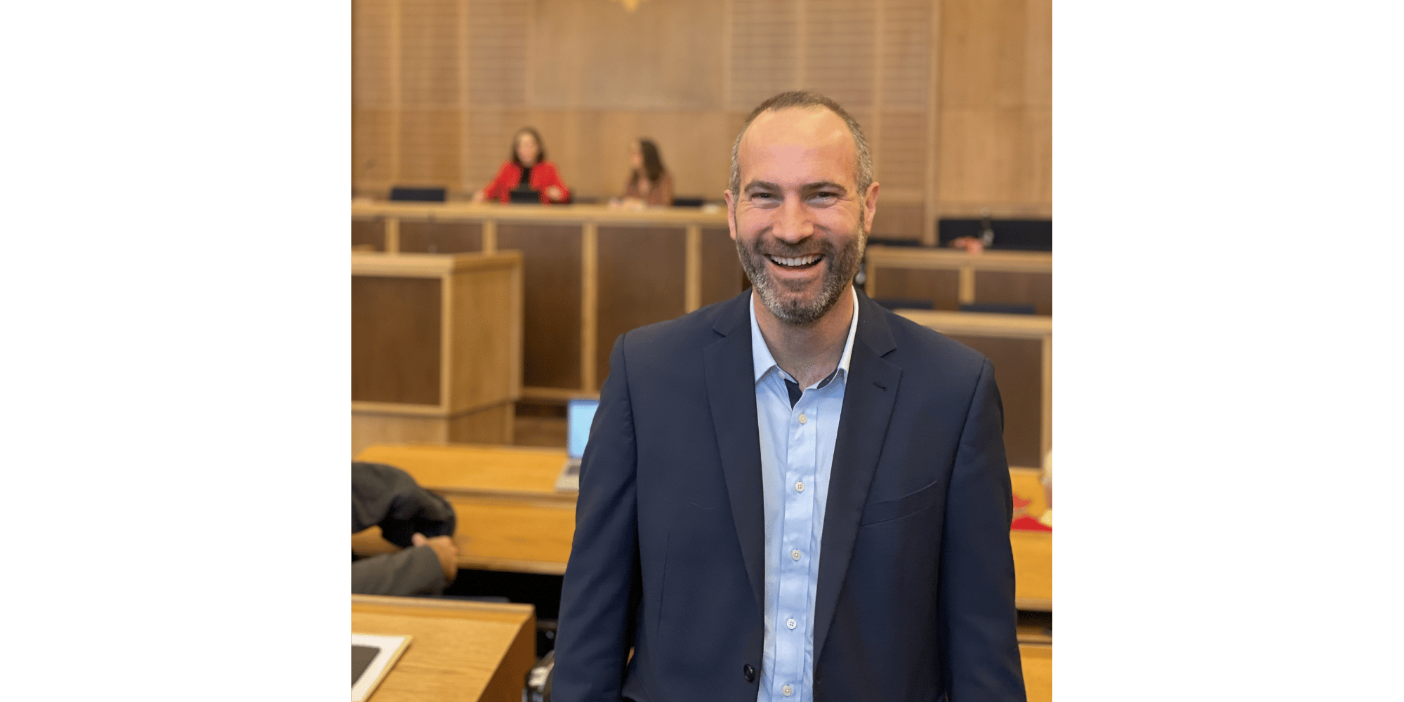 Mann stehend und lächelnd im  dunklen Anzug
