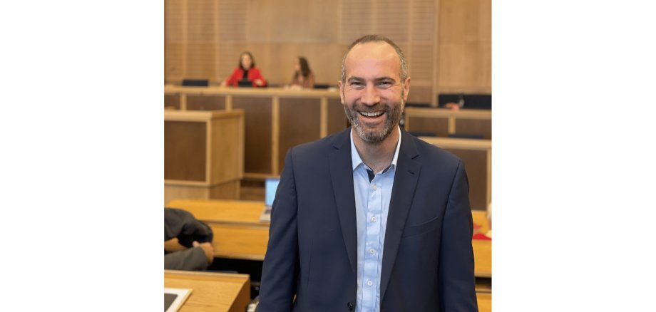 Mann stehend und lächelnd im  dunklen Anzug