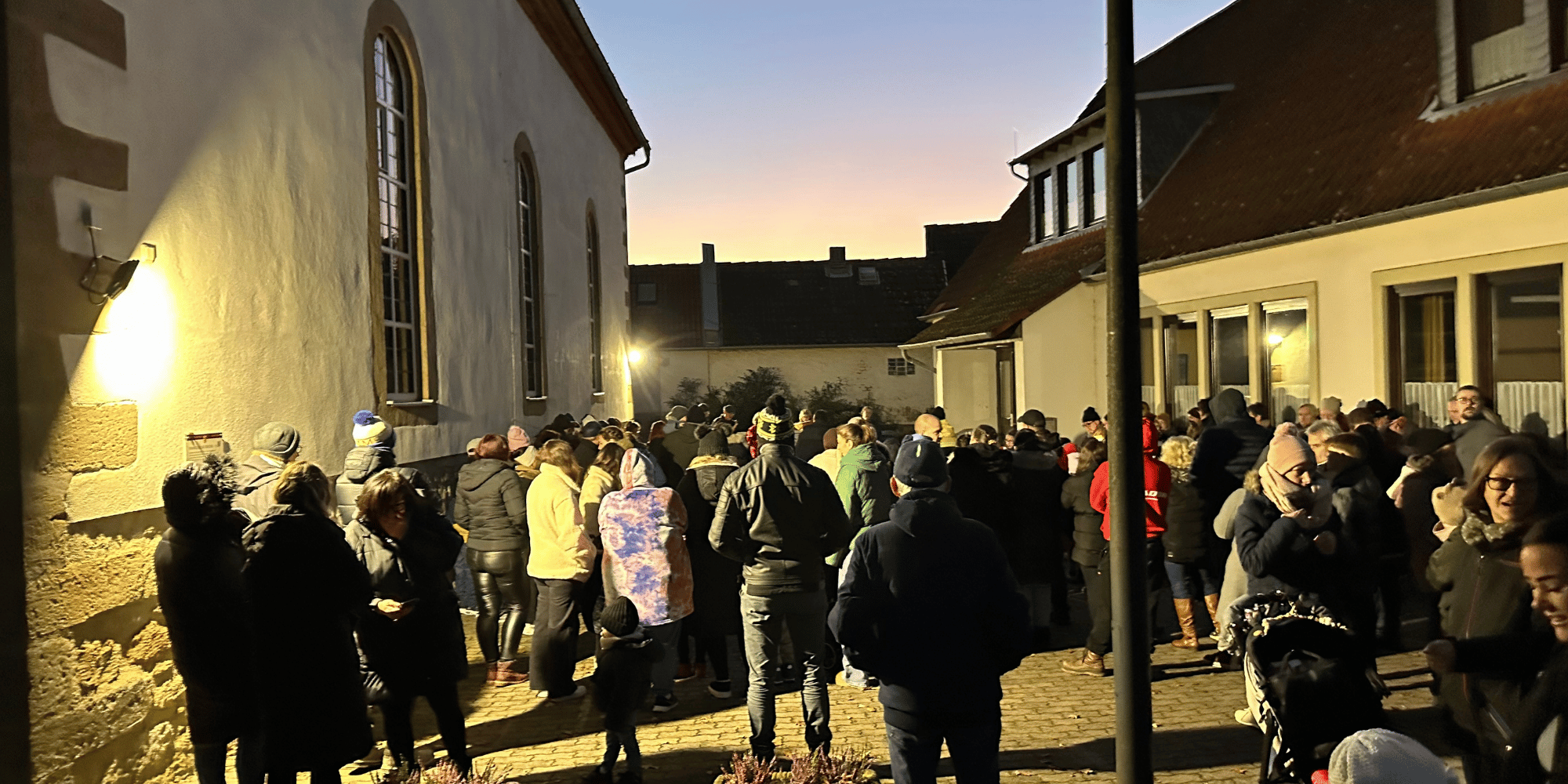 Mehrere Kinder und deren Eltern mit Laternen auf einem Platz