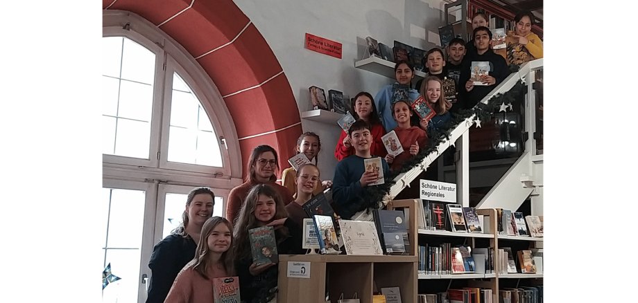 Mehrere Kinder auf einer Treppe stehend hinter einem großen Bürcherregal
