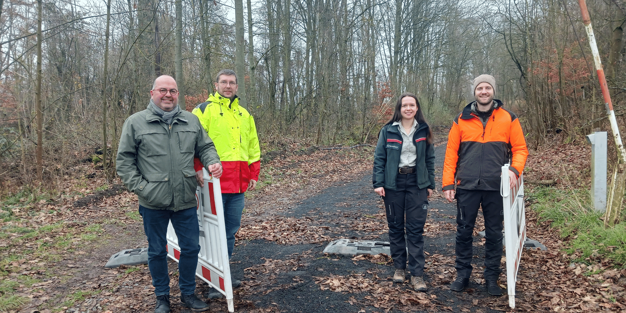 3 Männer und 1 Frau stehend im Wald
